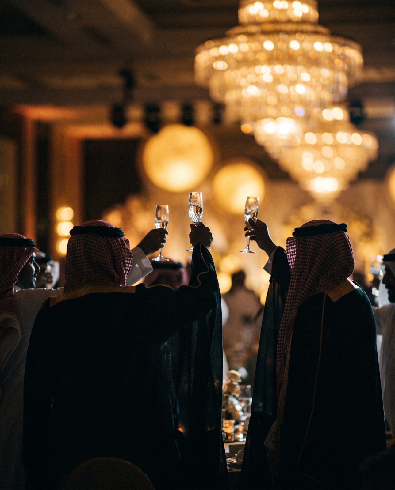 Guests raising crystal flutes beneath the chandelier